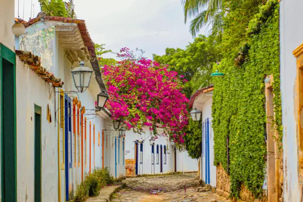 Rua de pedra com casas coloniais coloridas e flores em Paraty (RJ), representando o turismo sensorial por estação no Brasil.