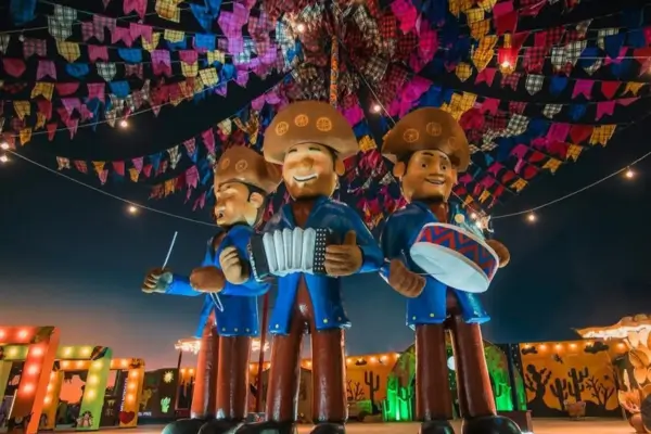 Bonecos de músicos nordestinos sob bandeirinhas coloridas no São João de Itatim, na Bahia, representando a cultura junina do inverno brasileiro.