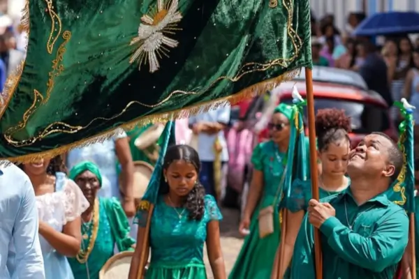 Procissão da Festa do Divino Espírito Santo em Alcântara, Maranhão, com devotos vestidos de verde carregando bandeira simbólica.